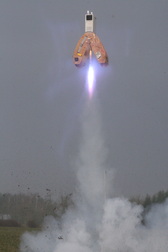 A model rocket lifting off from a launch pad as Jive coworkers watch
